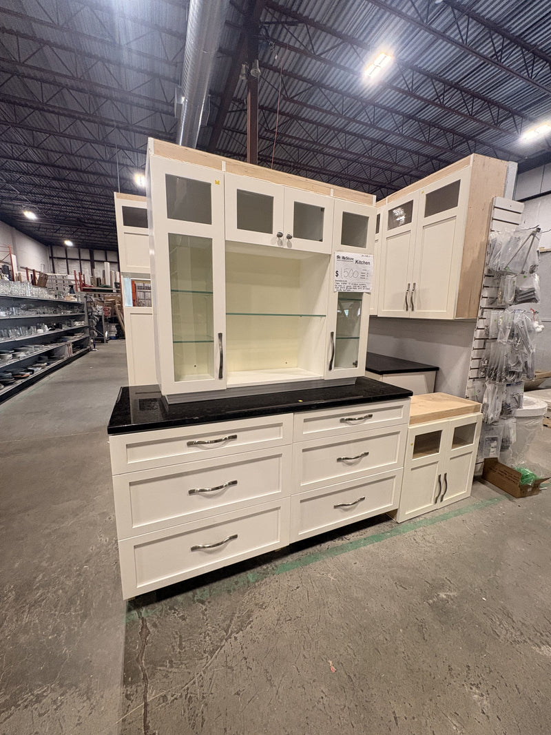 White Kitchen with Glass Accented Doors, Black Granite, and a Statement Wall Unit