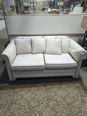 Cream loveseat with brown piping